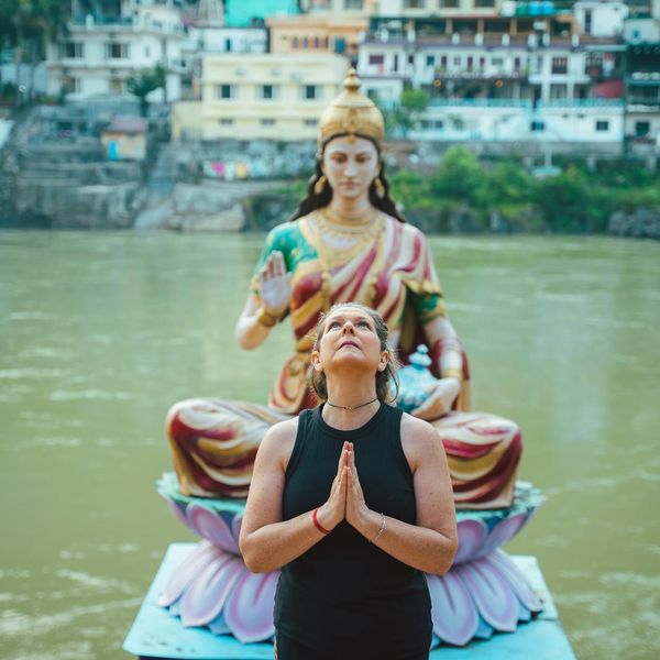 Person meditating outdoors with a serene natural background.