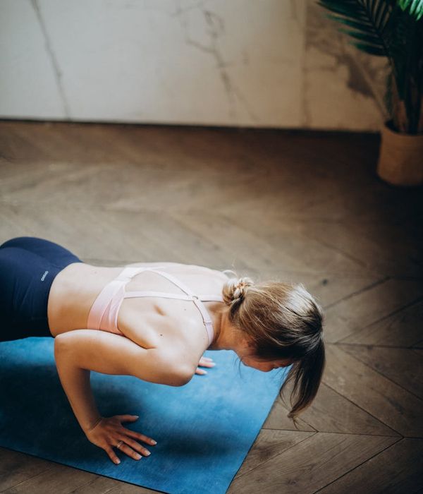 Woman in a calm yoga pose in a warmly lit room.